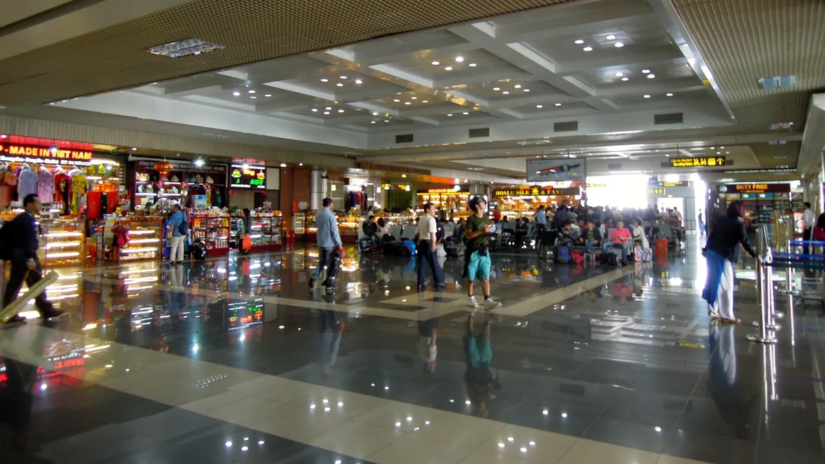 Travelers walk through a departure lounge lined with shops and duty-free stores at Noi Bai International Airport in Hanoi.